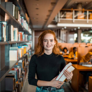 Close up portrait of a young woman holding a book in a library